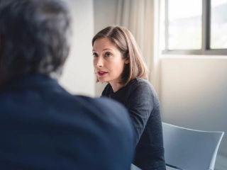 Mitarbeiterin diskutiert mit einem Mitarbeiter in einem Sitzungszimmer